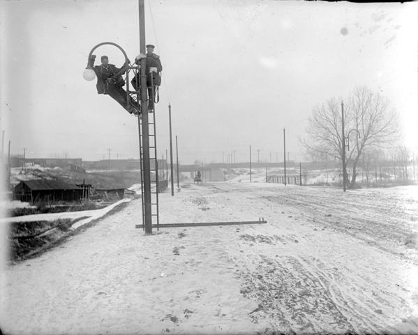 Men installing street lights on Alameda Ave. in Denver, Colo.