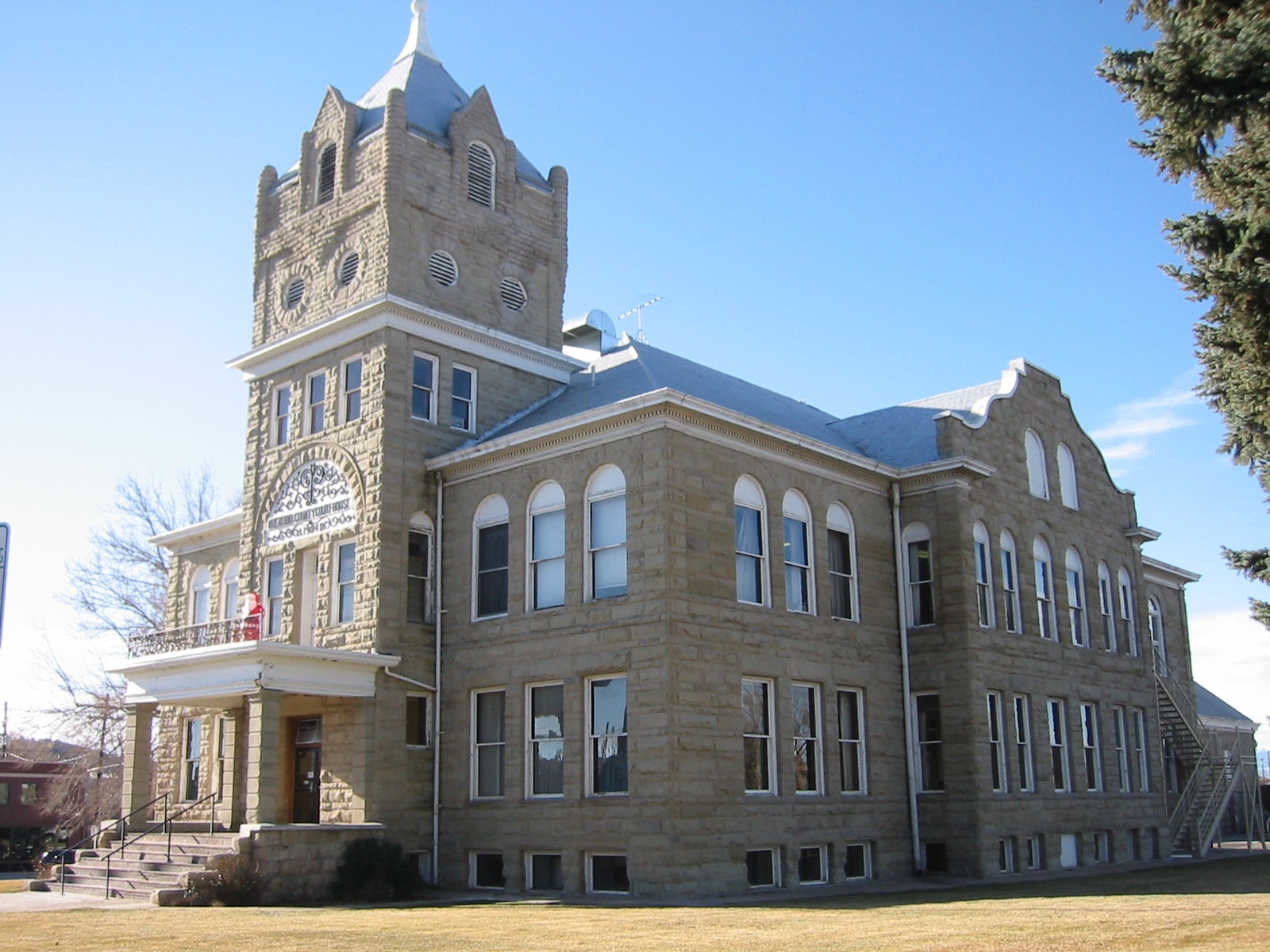 A photo of the historic Huerfano County Courthouse and Jail, a stone, multi-level building with a prominent tower.