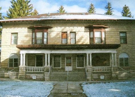 A large two-story stone home with a covered front porch.