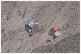 A distant view of an old mine boarding house and a tramhouse. Each building is sitting on the side of a hill.