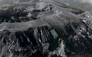A black and white photo of the road on a steep treeless ridge.