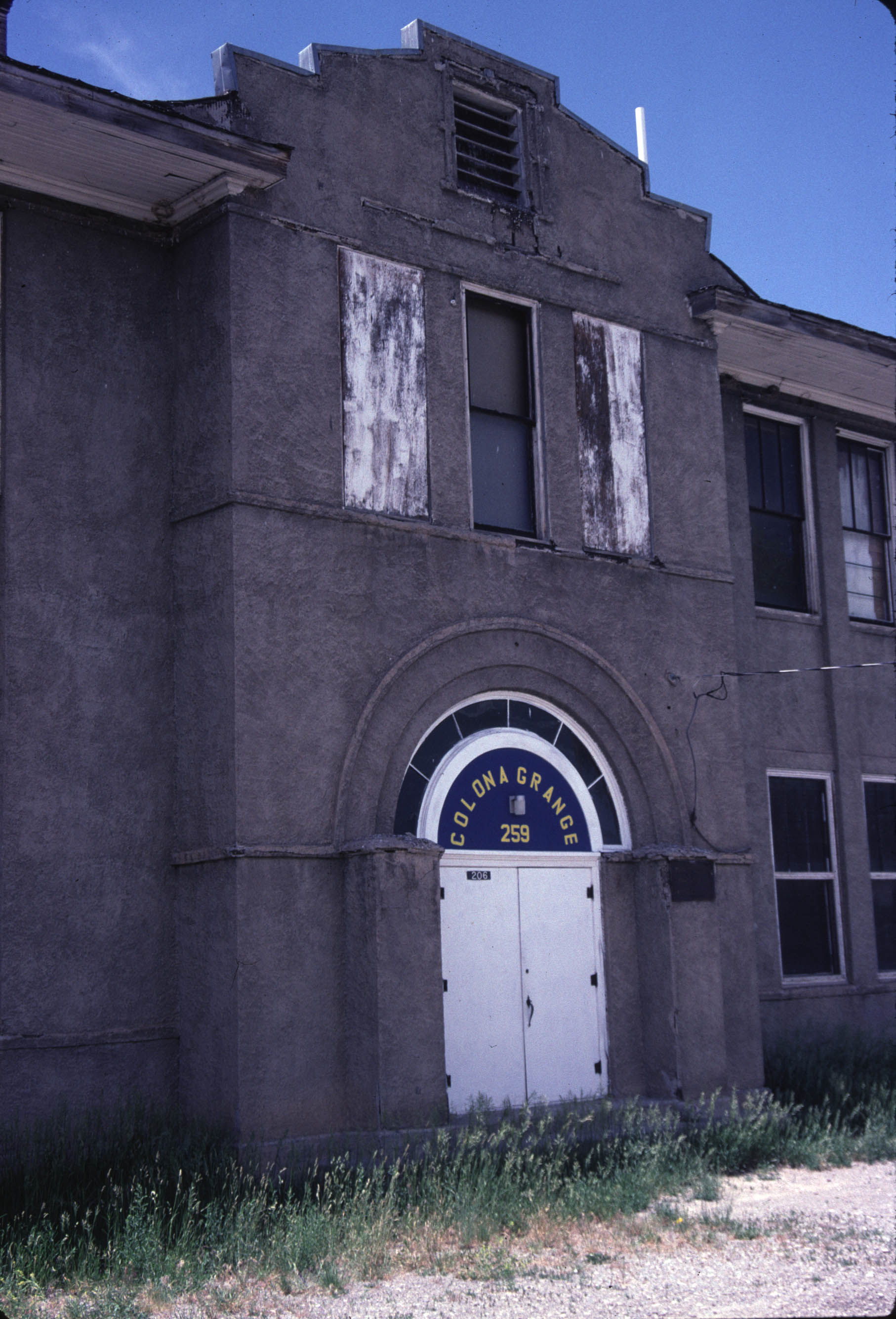 Colona School doorway with a sign above it reading "Colona Grange 259".  Boarded up windows are above the door.  Photograph from 2001.
