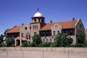 A photo of the building with currvilinear gables and large silver dome in the center.