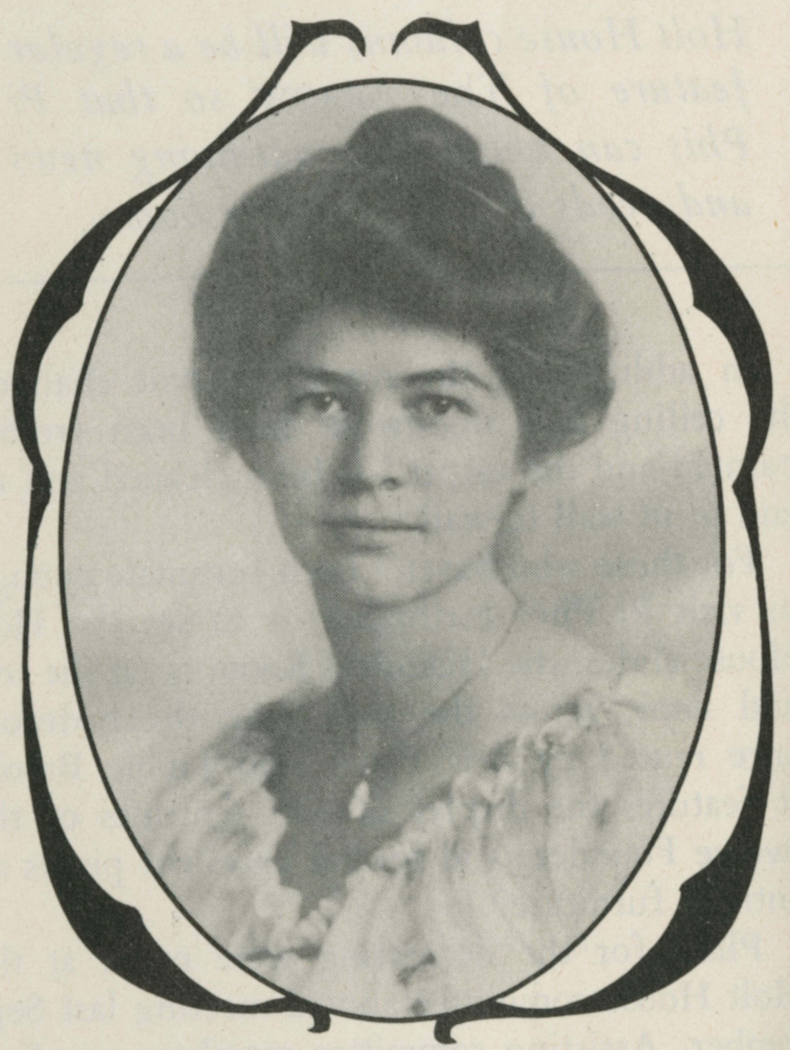 Photo of a young woman, posing for a portrait. She wears a light colored blouse with small ruffles around the neckline, and a pendant necklace. She is fair-skinned with dark hair that is pulled up into a bun at the top of her head. She has a faint smile on her face.