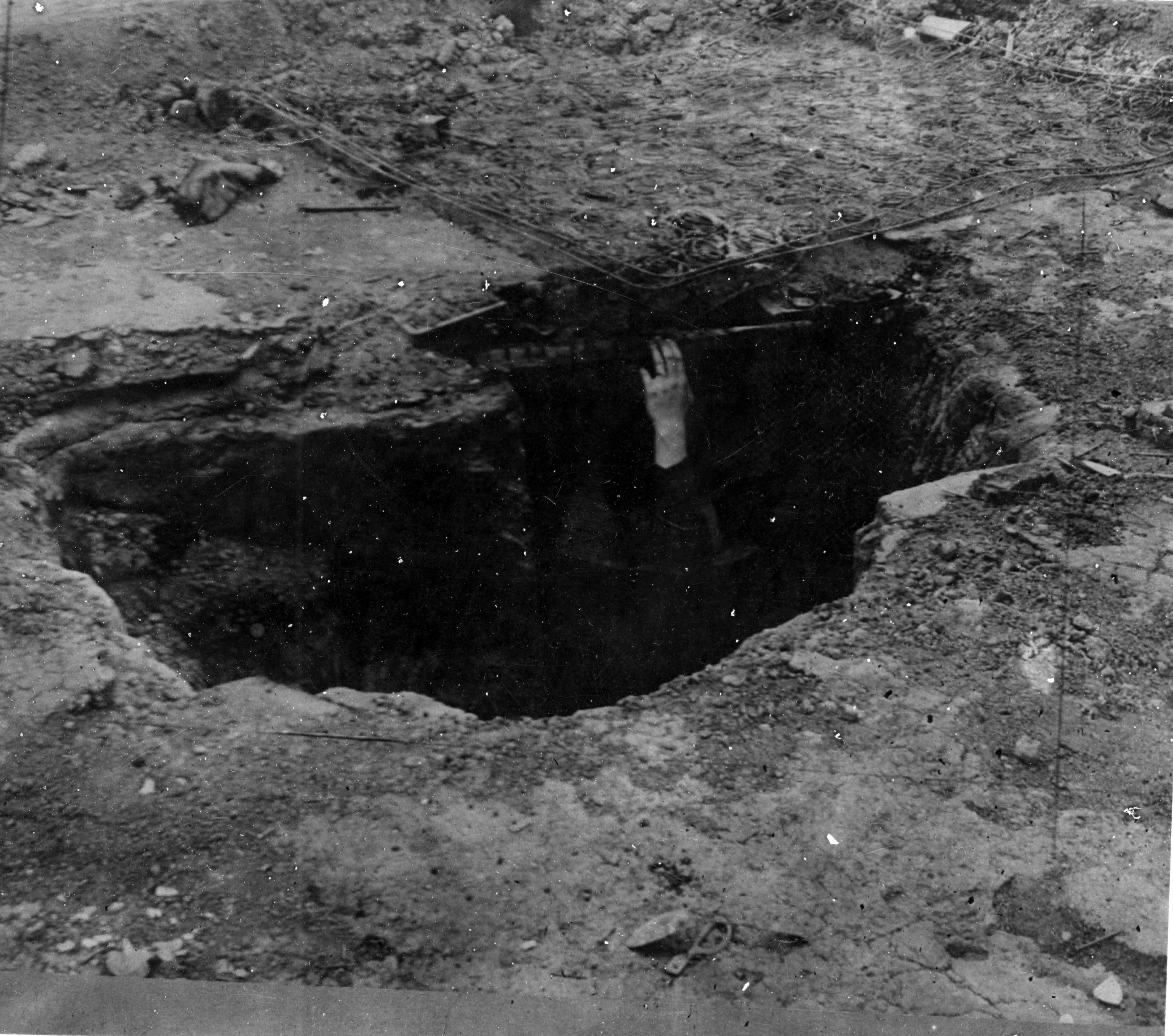 A hand reaching out of a hole in the ground.