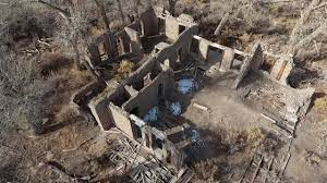 Photo of the ruins of a multi-room building, which now has no roof and the walls are exposed to the elements. This is an aerial view of the building site.