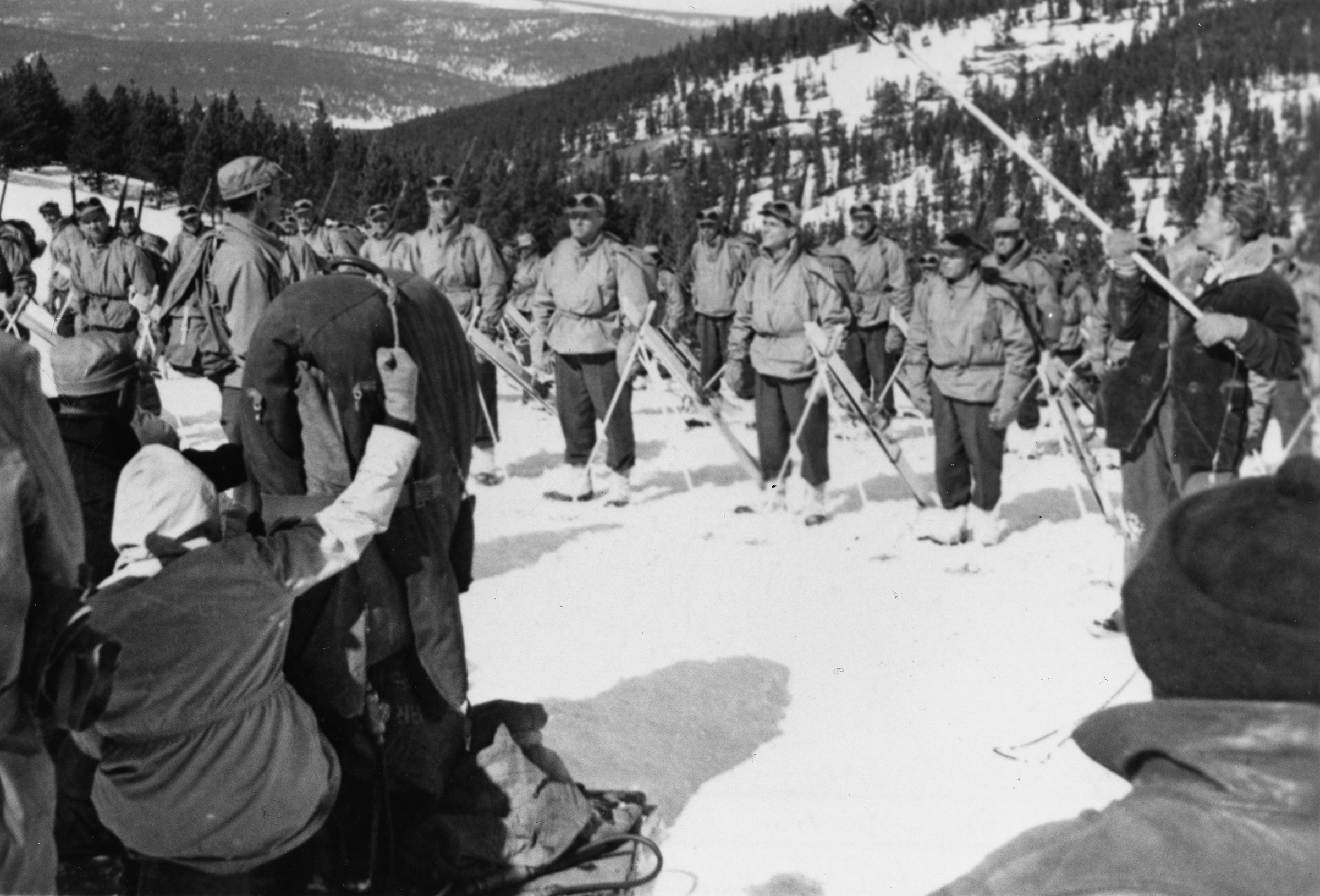 A team of filmmakers on a snowy mountainside with men in skis.