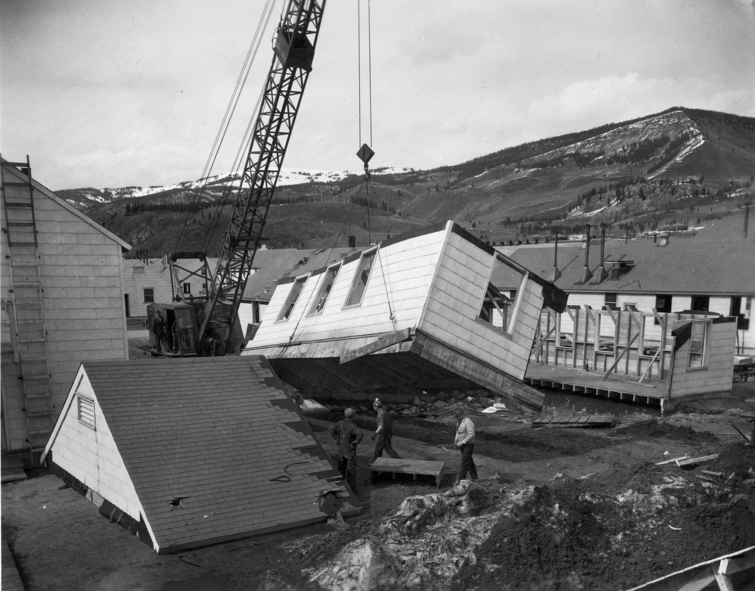 A building being demolished with the use of a crane.
