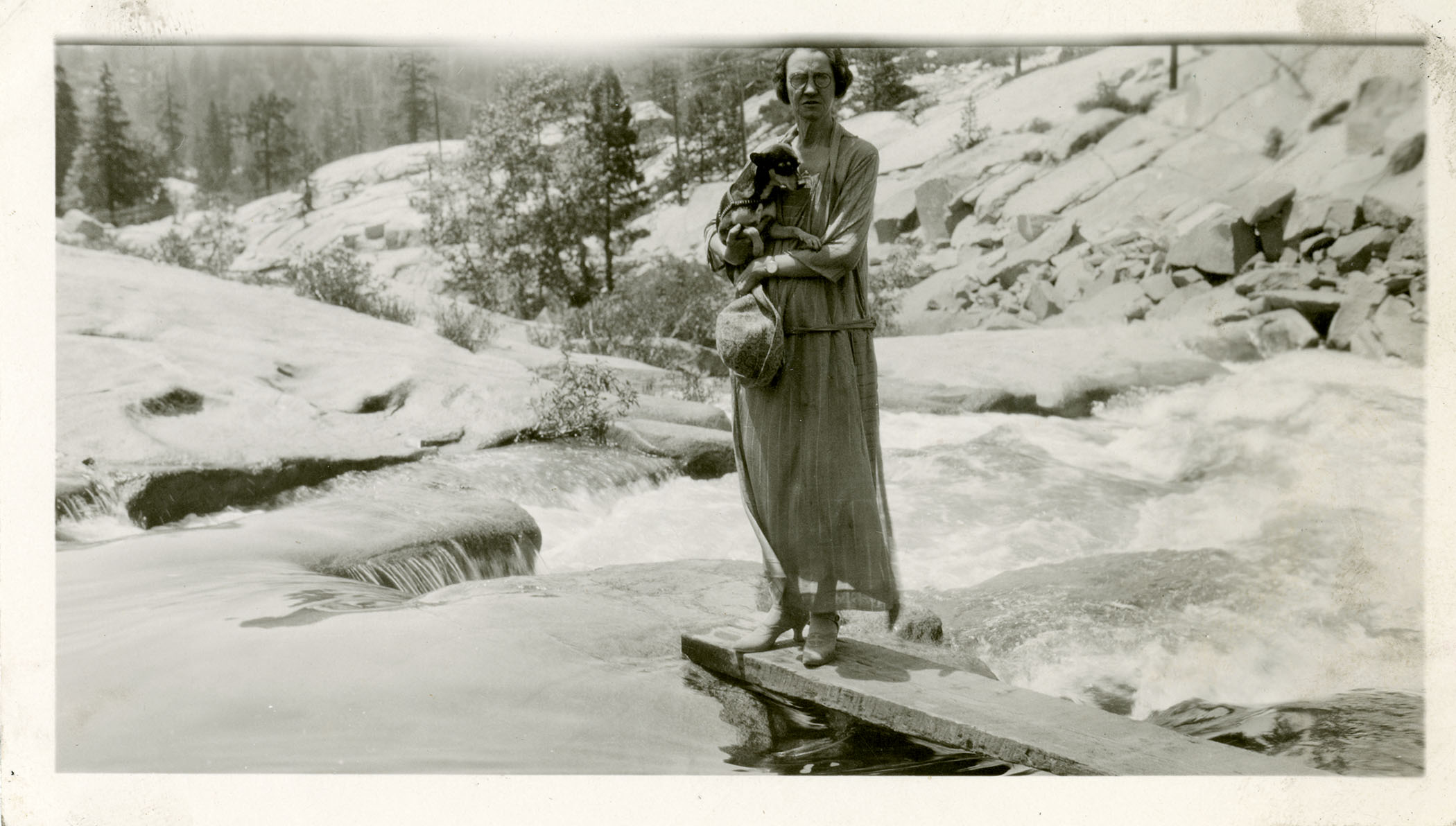 Laura Evans holding her dog, Mister Pimp Powers, while standing near a river.