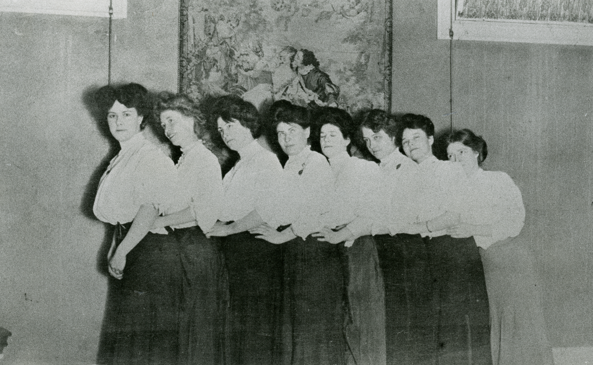 Madam Anna “Gouldie” Gould’s boarders lined up in front of a tapestry