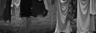A string of clothes, including some for adults and some for children, hanging from a laundry line outside a building.