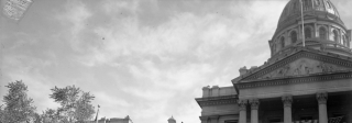President Franklin D. Roosevelt sits behind a podium in front of the Colorado State Capitol building.