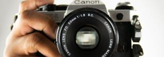 A Canon-brand camera being held by a person's hand. The person is not visible.