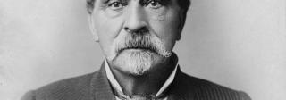 Black and white photograph of Barney Ford looking into the camera, wearing a suit jacket and a tie.