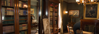 The dark wood library at the Center for Colorado Women's History. There are many books on the shelves and a brass engraved art piece.