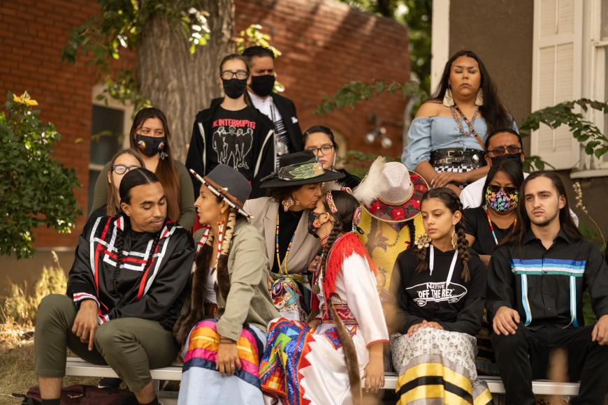 A group of Native and Indigenous adults and youths sitting and talking in front of the Baca House at Trinidad History Museum.