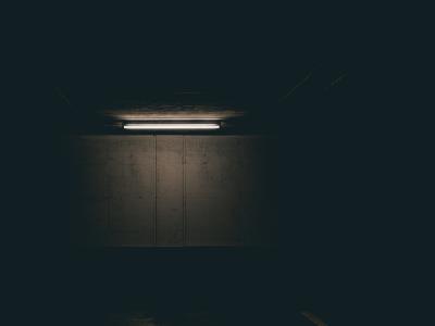 Photo of a single flourescent bulb faintly illuminating the dark.