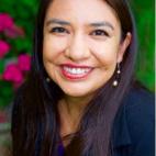 Photo of Kathryn Redhorse. She has long, straight, dark hair and is wearing a navy blue jacket and a blue blouse. She is smiling.