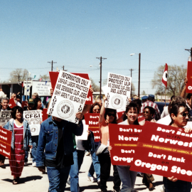 A marching protest of Pueblo steelworkers and supporters. They carry signs reading "Don't Bank with Northwest. Don't Bank on Oregon Steel."